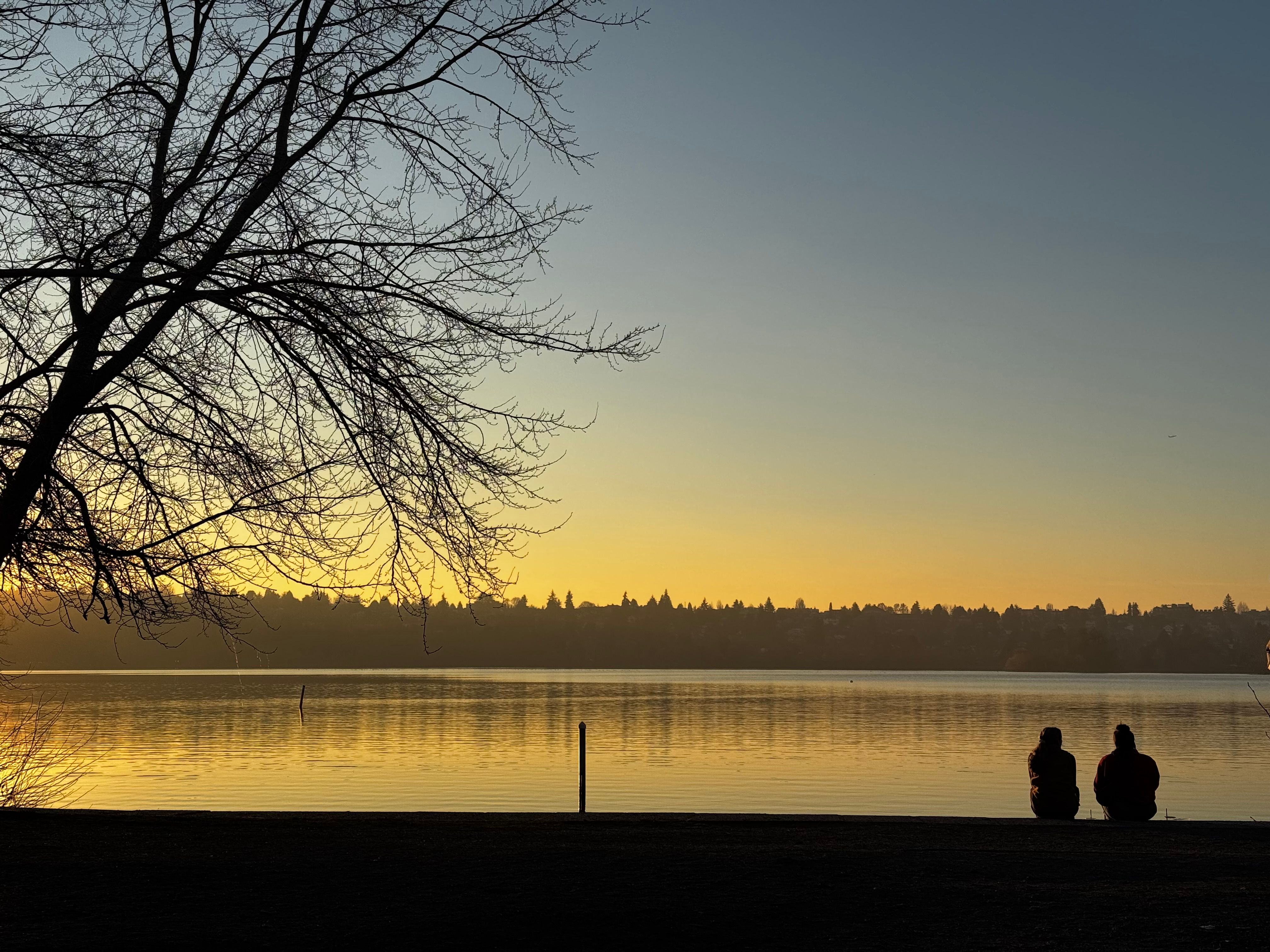 A couple watches the sunset at Green Lake